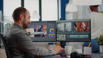 maker editing movie using post production software working in creative start up agency office with two monitors. Videographer processing audio film montage on professional computer, taking notes video