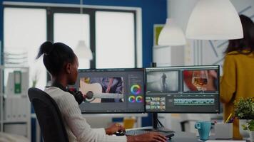 African editor looking at camera smiling editing project in post production software working in creative studio office. Videographer editing audio film montage on professional computer video