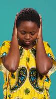 Vertical Moral person doing three wise monkeys symbol in studio, covering her eyes, mouth and ears against blue background, See no evil, speak no evil and hear no evil metaphor, wisdom concept. Camera A. video