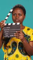 Vertical Female film producer using a clapperboard to say action in movie industry and cinematography. Skilled filmmaker woman cutting a scene with filming slate, production. Camera A. video