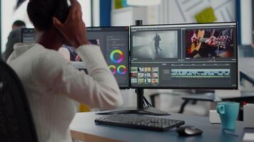 African editor working with footage and sound, editing new project cutting film montage sitting in modern agency office. Woman using computer processing movie in post production software video