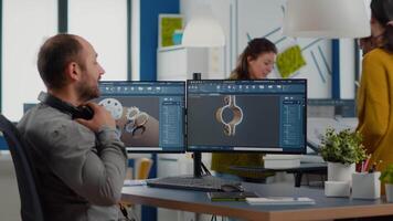engenheiro com fone de ouvido trabalhando em pc, tela mostrando cafajeste Programas com 3d construção metálico componentes. arquitetos usando caneta caneta desenhando industrial projeto, estudar a projeto dentro criativo agência video