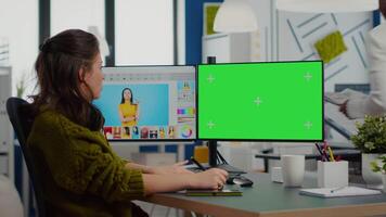 Woman retoucher working on photo set in photo editing software using greenscreen, chroma key isolated display of computer. Content creator doing portrait retouching in digital multimedia company video