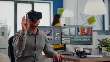 editor experiencing virtual reality headset, gesturing, editing film montage using post production software working in creative agency office. Videographer using VR goggles in multimedia company video