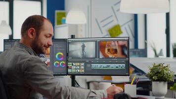 Videographer putting on headset editing project using post production software working in in digital multimedia company with two monitors. Retoucher processing audio film montage on computer video