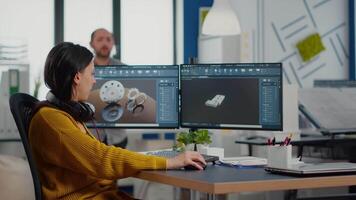 Industrial designer holding tablet discussing with woman engineer while working in CAD program, designing new components, comparing 3D prototype with project from notepad, using pc with two monitors video
