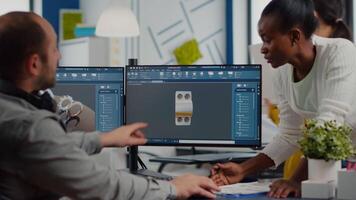 Multiethnic team sharing ideas about industrial project using dual displays setup with 3D gears and metalic clamp using CAD software. Industrial engineer and black manager working in creative office video