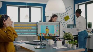 Retoucher putting on headphones retouching image using stylus pen, listening music while working on PC with two displays. Woman editing in software app with graphic tablet sitting in creative agency video