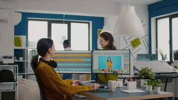 Two photographers advising for retouching client photo in creative media agency office. Graphic designers working at client assets on PC with two displays in photo editing software holding stylus pen video