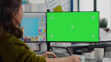 Creative woman retoucher editing assets in digital retouching program, working concentrated in photo production studio looking in computer with green screen, chroma key mockup isolated display. video
