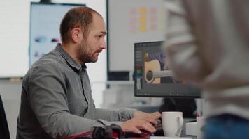 Man editor looking at camera, working with footage and sound on computer with two displays. Videographer editing movie smiling at camera, using app software for film montage in startup office. video