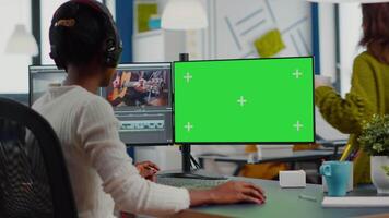 Black videographer using computer with chroma key, mock up isolated display editing and audio footage. Woman editor processing film montage on green screen working in digital multimedia company video
