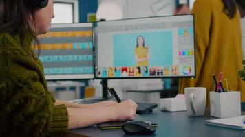 Creative photographer using digital retouching program, wearing headset editing photos for client. Stylish retoucher, graphic editor working in digital multimedia workplace at pc with two monitors video