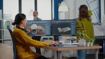 Industrial female engineer looking at personal computer with dual monitors setup, screens showing CAD software with 3D prototype of gears metalic mechanical piece. Employee working in creative office video