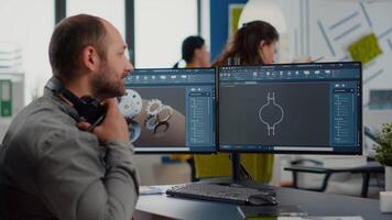 Designer engineer putting on headphones working with technical cad program, analysing 3D gears prototypes, drawing with stylus pencil. Industrial architect studying prototype idea on computer video