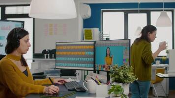 Focused retoucher specialist working at computer in creative office environment wearing headset. Color designer editing fashion photograph in digital graphics editing software with stylus pencil video
