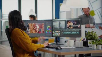 Colleagues discussing about project adjusting film footage working in creative start up agency office with two monitors. Videographers processing movie montage with post production software video