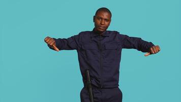 Security guard doing thumbs down sign gesturing, denying public access in restricted area. Portrait of bodyguard doing negative hand gesture, being dismissive, studio background, camera B video