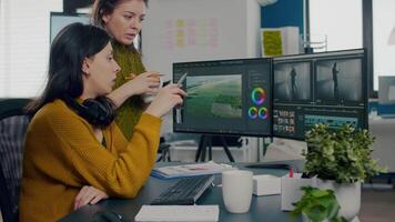 Women videographers editing project creating content, team of bloggers sitting in modern start up office studio. Manager explaning to colleaque film montage working in post production software. video
