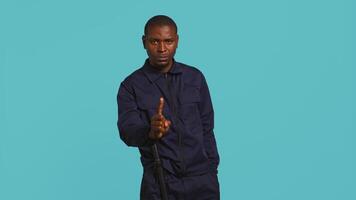 Portrait of security guard doing no gesturing with finger, prohibiting access while overseeing premises. Private law enforcement worker barring people from entering place, studio backdrop, camera B video