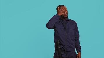 Portrait of tired security guard suffering from painful headache while overseeing premises. Private law enforcement worker feeling ache from fatigue, studio backdrop, camera B video