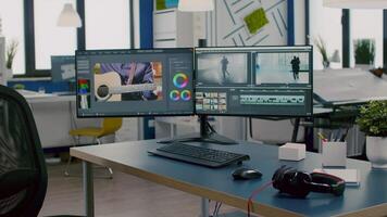 Modern creative workplace with nobody in and dual displays setup processing film montage. editing start up studio company with no people in it and post production software on pc displays video