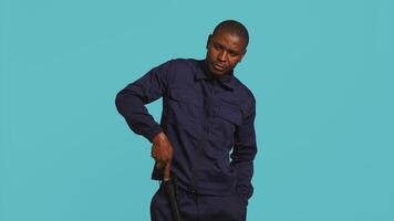 Portrait of security guard menacingly smacking hand with baton while overseeing premises. Private law enforcement worker cautioning trespassers with truncheon, studio backdrop, camera B video