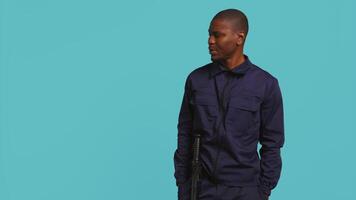Portrait of security guard looking around while overseeing premises. Private law enforcement worker doing surveillance job, inspecting location, studio backdrop, camera B video