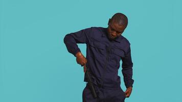 säkerhet vakt avlägsnande batong från bälte, framställning till ge sig på misstänkta. porträtt av livvakt pekande finger mot batong, hotfull till dämpa brottslingar, studio bakgrund, kamera b video