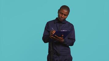 Portrait of security agent holding clipboard, taking notes, receiving orders to secure assigned post, studio background. Guardian maintains logs of observations, handling security breaches, camera B video
