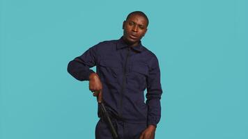 Portrait of security agent securing assigned post, smacking hand with baton to appear intimidating. Guardian does threatening gesture with truncheon, handling security breaches, camera B video