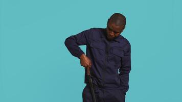 porträtt av säkerhet ombud avlägsnande batong från bälte, använder sig av den till säkra tilldelad posta, studio bakgrund. afrikansk amerikan väktare pekande finger till batong, hantering säkerhet överträdelser, kamera b video