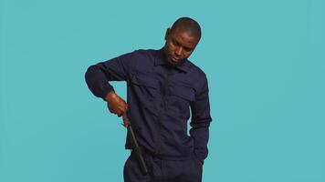 Security guard smacking hand with baton, intimidating suspects. Portrait of bodyguard showing truncheon, threatening to subdue criminals, shaking head, studio background, camera B video