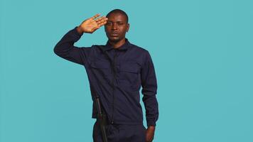 Security guard doing salute hand gesture, preparing to start job of deterring criminals. Portrait of bodyguard doing greeting gesturing and military pose, studio background, camera B video