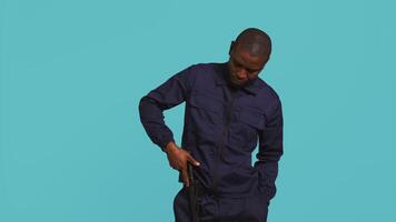 Portrait of security staff member tasked with evicting trespassers, intimidating them with baton. Patrolling agent maintains secure environment using truncheon weapon, studio background, camera B video