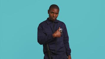 Sécurité garde empêcher criminel activité, menaçant suspects avec actif caméra corporelle. portrait de menaçant garde du corps montrer du doigt vers Sécurité corps caméra, studio arrière-plan, caméra b video