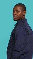 Vertical Portrait of security guard overseeing premises to prevent intrusion hearing suspect sounds, turning around. Private law enforcement worker standing isolated with back against studio backdrop, camera A video