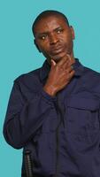 Vertical Security guard doing thinking hand gesture, being tasked with preventing criminal activity and detaining suspects. Portrait of pensive bodyguard rubbing chin, studio background, camera A video