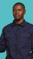 Vertical Upbeat security guard greeting people, preventing criminal activity and detaining suspects performing crimes. Portrait of jolly bodyguard waving hand towards visitors, studio background, camera A video