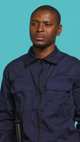 Vertical Portrait of security guard overseeing premises to prevent unwanted intrusion waving hand towards visitors. Private law enforcement worker doing greeting gesturing, studio backdrop, camera A video
