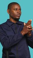 Vertical Security guard doing pretending to shoot gun hand gesture while being tasked with preventing criminal activity. Portrait of bodyguard doing pistol fingers gesturing, studio background, camera A video