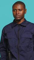 Vertical Portrait of security agent securing assigned post, pretending to shoot gun, studio background. African american guardian prepared to handle security breaches, doing pistol fingers gesturing, camera A video