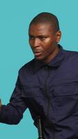 Vertical Portrait of security guard catching intruder with flashlight while overseeing premises. Private law enforcement worker calls over trespasser after detecting him with lantern, studio backdrop, camera A video