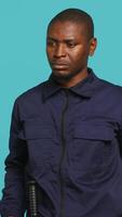 Vertical Portrait of security guard overseeing premises to prevent intrusion turning on flashlight to detect suspects. Private law enforcement worker using lantern device, studio backdrop, camera A video