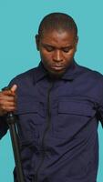 Vertical Portrait of security guard overseeing premises, turning on flashlight and preparing baton to detain suspects. Private law enforcement worker using lantern and truncheon gear, studio backdrop, camera A video