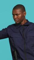 Vertical Security guard pointing finger at people to prevent them from gaining access in restricted areas. Portrait of stern bodyguard scolding and telling off unwanted visitors, studio background, camera A video