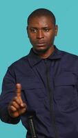 Vertical Security guard doing no gesturing with finger, prohibiting public access in restricted area. Portrait of stern bodyguard barring people from entering place, studio background, camera A video