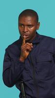 Vertical Portrait of security guard doing shush sign gesturing with finger to intruder while overseeing premises. Private law enforcement worker urging people to keep quiet, studio backdrop, camera A video