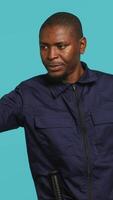 Vertical Portrait of security guard doing stop sign gesturing to intruder while overseeing premises. Private law enforcement worker showing halt hand gesture to trespasser, studio backdrop, camera A video