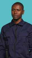 Vertical Portrait of smiling security agent securing assigned post, isolated against studio background. African american guardian prepared to handle security breaches and diffuse tense situations, camera A video